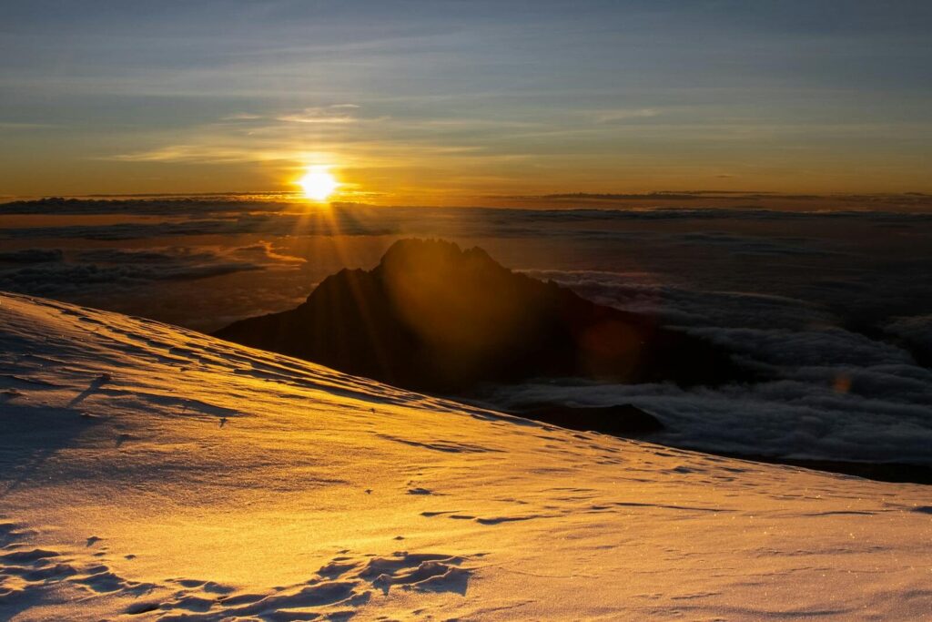 Golden sunrise over a snowy mountain landscape captured at high altitude.